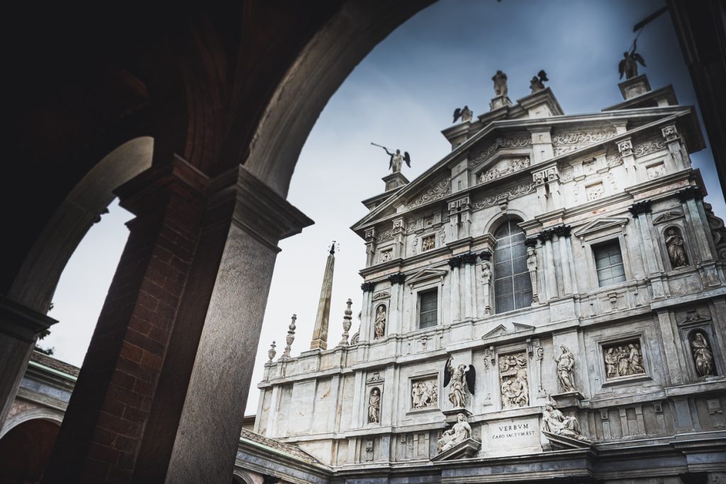 Un suggestivo scorcio della facciata della Basilica di San Maria dei Miracoli catturato da uno dei portici circostanti, offrendo una prospettiva unica sulla magnificenza architettonica